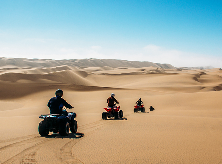 Friends riding quadbikes in sunny desert, Swakopmund, Namibia